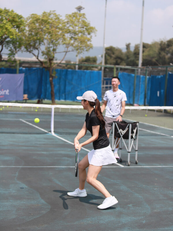 tennis coach and a female student hitting the ball.